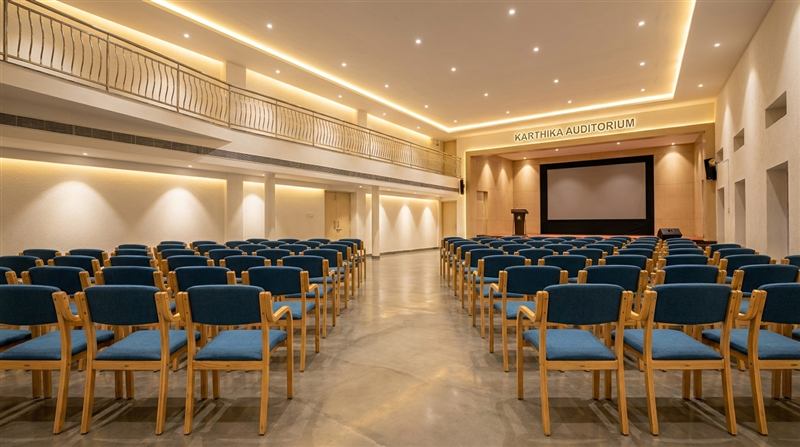 Conference setup with projector screen and rows of upholstered chairs